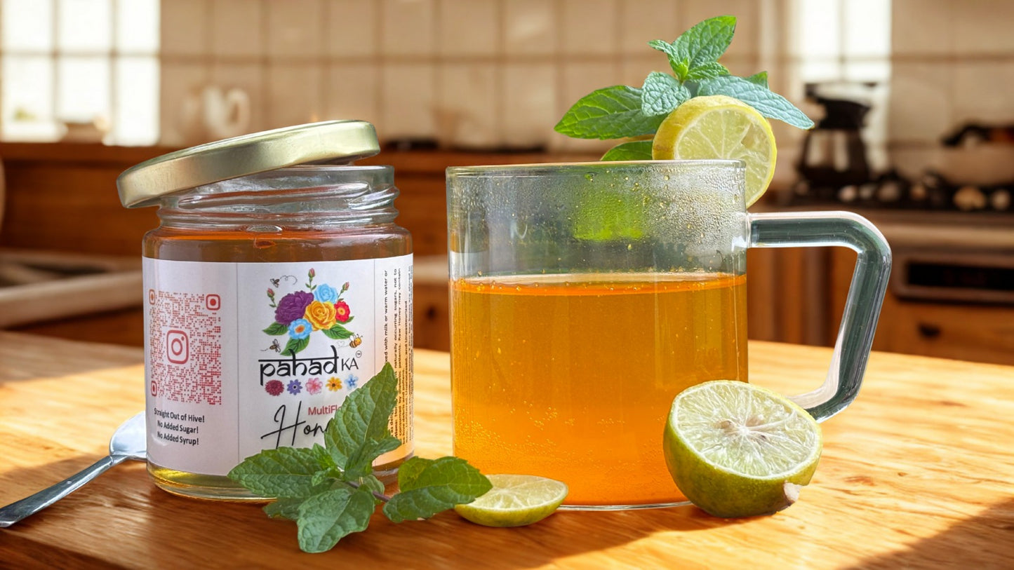 Jar of honey with a label, glass of honey water with lemon and mint, on a kitchen counter.