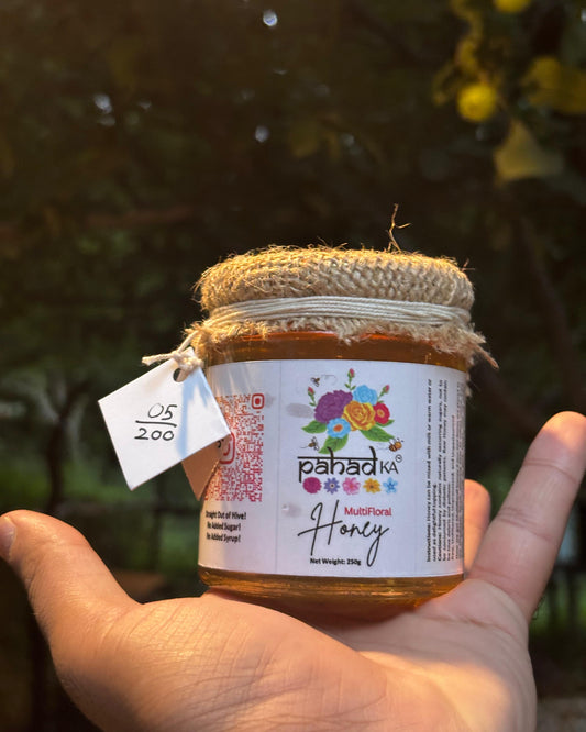 Jar of honey held by a hand with a blurred natural background
